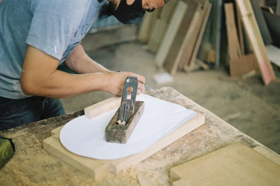 Menuisier LAMA BOIS travaillant le bois au rabot dans son atelier