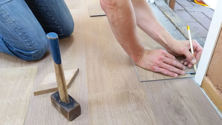 Menuisier posant des lames de parquet au maillet
